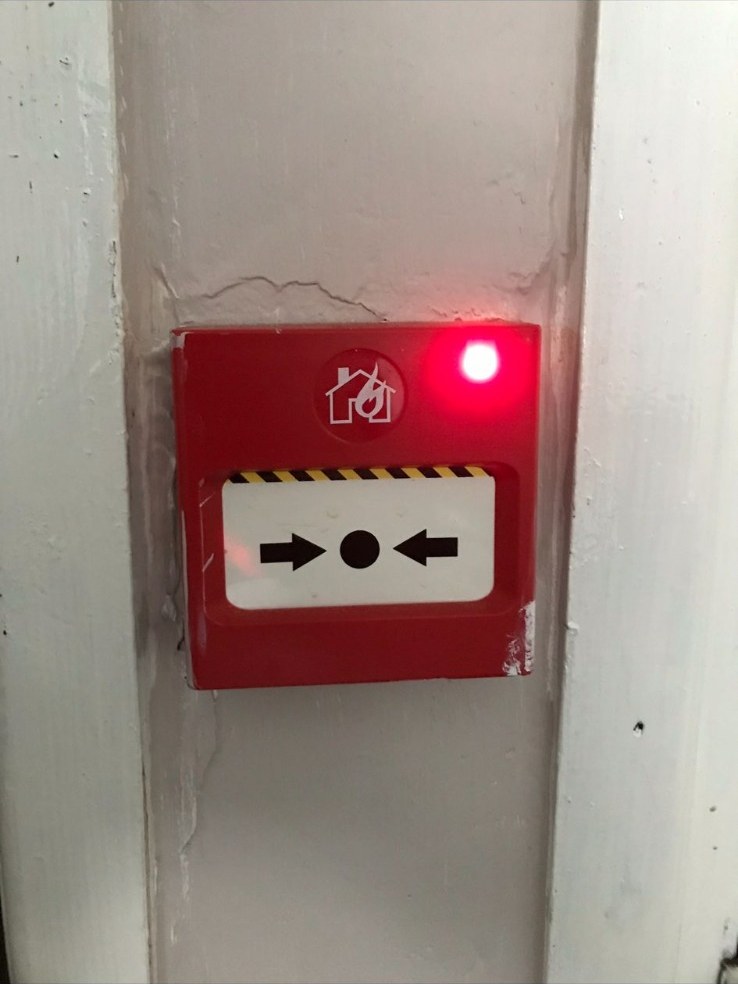 Addressable fire alarm manual call point with active red status LED after installation.