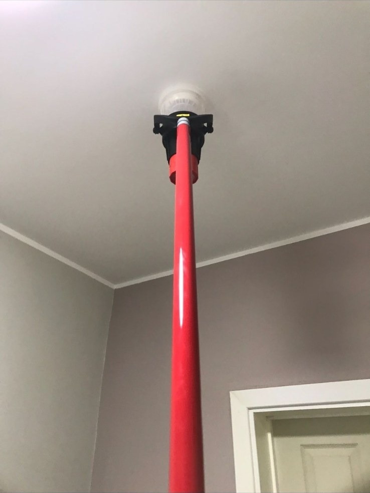 Ceiling smoke detector being tested with a service pole